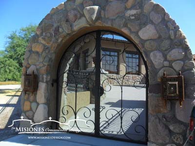 black large open scrolls steel metal courtyard gate set in rock wall