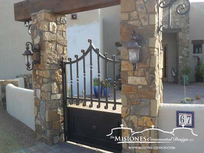 rust or brown colored, single small gate with pointed arch set in rock pillars, steel metal courtyard gate