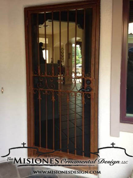 security screen door with vertial bars with simple scrolled band design in the center of the door, in a rust finish